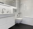 modern bathroom, white tiles, black tiles, white sink, white toilet, bathtub, shower