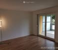 empty room with wooden floor, white walls, floor lamp, sliding glass door leading to balcony