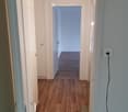 Empty corridor with wooden floors, white walls, doors leading to other rooms