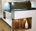 Modern kitchen with white cabinets, black countertop, wooden accents, and decorative vases on the counter.