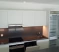 Modern kitchen with white cabinets, stainless steel appliances, and a dark brown countertop.