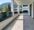 Modern balcony with large glass windows, tiled floor, and scenic mountain view.