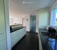 Modern kitchen with white cabinets, black countertops, and a double sink. The space features sleek, contemporary design with a large window providing natural light.