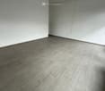 Empty room with light grey walls and a grey tiled floor, featuring a white ceiling with visible lighting fixtures.
