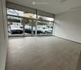 Empty room with large glass doors leading to a parking area, tiled floor, and white walls.