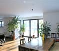 Bright, open dining area with large sliding glass doors leading to a balcony, wooden table, chairs, and several potted plants.