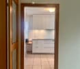 entrance hallway with wooden door, tiled floor, white cabinets, power outlet, tiled countertop, wooden desk, handbag