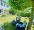 Garden with a grassy area, a tree, and outdoor furniture including a table and chairs.