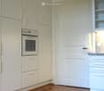 Modern kitchen with white cabinets, built-in oven, and granite countertop.