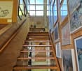 Corridor / Hallway. Wooden staircase with handrails, large windows, and framed artwork on the walls.