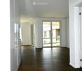 Empty room with wooden flooring, white walls, and large glass doors leading to a balcony.