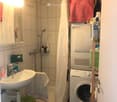 Bathroom with a sink, shower, washing machine, and various toiletries.