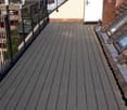 Roof terrace with wooden floor, metal railing, and a view of the city