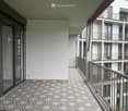 Balcony with patterned tile flooring, glass sliding doors, metal railing, and view of neighboring building.