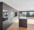 Modern kitchen with sleek cabinetry, a central island, and large windows offering a scenic view.