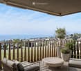 Balcony with a scenic view of a lake and town, featuring a lounge chair, a small table, and potted plants.