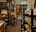 A well-lit, rustic interior with wooden shelves, a black chair, and various decorative items displayed on tables and shelves.