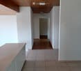 Empty hallway with white walls, wooden ceiling, tiled floor, and a glass cabinet on the left side.