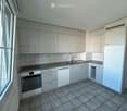Modern kitchen with white cabinets, tiled walls, and grey countertops. Features an oven, dishwasher, and sink.