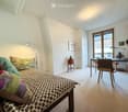 bedroom with a double bed, wooden headboard, nightstand, side table, lamps, bookshelf, desk with chairs, wardrobe, picture frame, glass door, balcony
