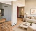 Modern open-plan living and dining area with light wood flooring, grey sofa, coffee table, dining table with chairs, pendant lamp, and decorative vases.