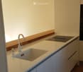 Modern kitchen with white cabinets, a single-basin sink, and a sleek faucet. The countertop is light-colored with a wooden backsplash.