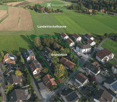 Aerial view of a residential area with multiple houses, surrounded by green fields and agricultural zones.