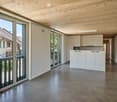 Open-plan space with white cabinets, a microwave, and large glass doors leading to a balcony.