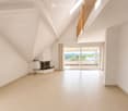 Bright, open living space with white walls, tiled floor, fireplace, large sliding glass doors leading to a balcony with scenic views.