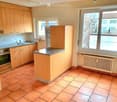 Modern kitchen with wooden cabinets, granite countertop, gas stove, refrigerator, sink, and windows
