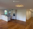 Modern kitchen with white cabinets, a kitchen island, and built-in oven, featuring wooden flooring and recessed lighting.