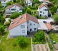 Aerial view of a residential neighborhood with multiple houses, gardens, and driveways.