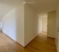 Empty hallway with wooden flooring and white walls, featuring several closed doors leading to other rooms.