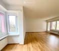 Empty room with wooden flooring, white walls, and multiple windows offering natural light. No furniture or equipment present.