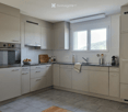 Modern kitchen with grey cabinets, stainless steel appliances, granite countertops, and a window overlooking a scenic view.
