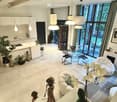 Modern living room with white sofa, glass dining table, pendant lights, kitchen island, and decorative items including statues and vases.