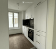 Modern kitchen with white cabinets, black countertop, and wooden flooring. Features an oven, sink, and ample storage space.