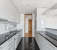 Modern kitchen with white cabinets, black countertops, stainless steel sink, and built-in stove. Features sleek design with integrated lighting and ample storage space.
