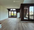 Empty room with wooden flooring, large windows, and a staircase leading to an upper level. No furniture or equipment visible.