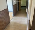 Empty hallway with wooden flooring, white walls, and several doors leading to different rooms.