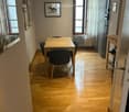 Dining area with wooden floor, table, chairs, and artwork on walls.