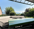 Balcony with a table and chairs, surrounded by greenery and a view of the landscape.