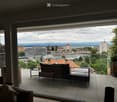 Balcony with a panoramic city view, featuring a sofa, chairs, and a small table.