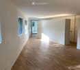Empty hallway with wooden flooring, white walls, and large windows allowing natural light to enter. The space is clean and minimalistic, with no furniture or decorations visible.