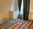 A cozy bedroom with a neatly made bed, a dresser, and a window with curtains.