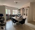 Modern kitchen with a dining area, featuring a table with chairs, a fan, cabinets, and various appliances.