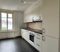 White cabinets, black countertops, stainless steel appliances, tiled floor, window with white frames, large window sill