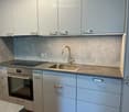 Modern kitchen with grey cabinets, stainless steel sink, faucet, and built-in oven.