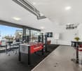 modern room with gray floors, white walls, large glass windows, foosball table, office chairs, plants, black carpet, table with chairs, whiteboard