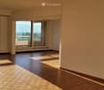 Empty room with wooden flooring, large sliding glass doors leading to a balcony with a scenic view of mountains and a construction site.